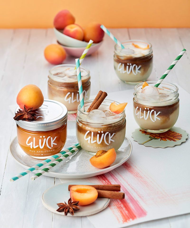 Aprikosen Spiced Latte im GLÜCK Glas, zur Deko Aprikosen und Zimt. Daneben ein Glas GLÜCK aus Aprikosen.