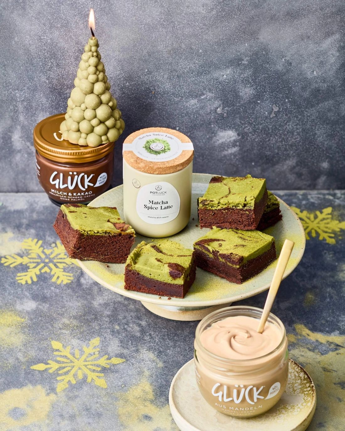 Matcha-Mandel-Brownies mit einem Becher POTLUCK Matcha Spice. Daneben zwei GLÜCK Cremes.