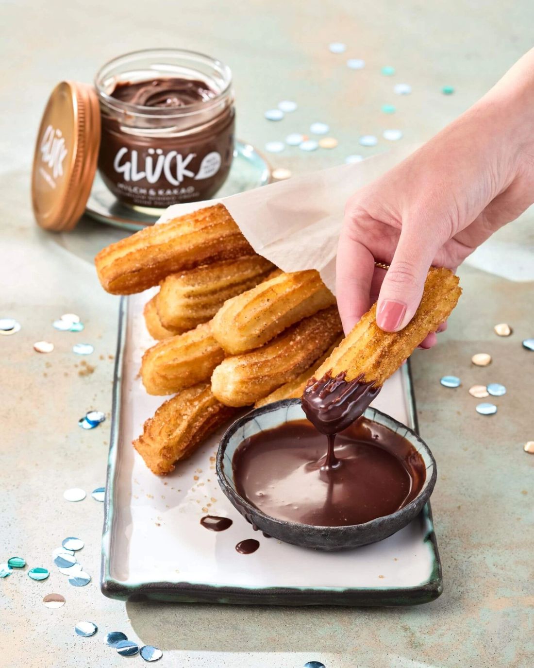 Churros mit Kakaodip. Dahinter ein Glas GLÜCK Milch & Kakao.