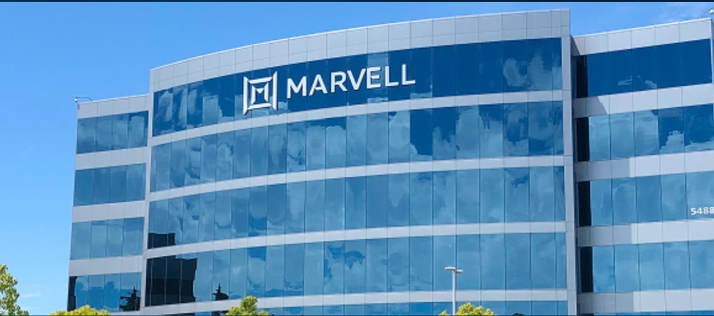 The image shows the exterior of a modern office building with large glass windows reflecting the sky. The prominent logo of Marvell Technology Group is displayed on the upper part of the building.