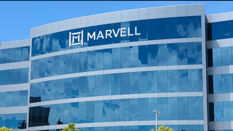 The image shows the exterior of a modern office building with large glass windows reflecting the sky. The prominent logo of Marvell Technology Group is displayed on the upper part of the building.