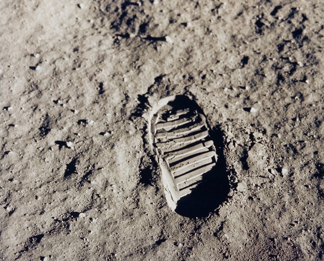 The image shows a clear footprint imprinted in the lunar surface, demonstrating the texture of the moon's regolith. The focus on the boot print indicates human presence during the Apollo missions. — Credit: Photo by NASA on Unsplash