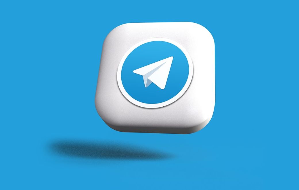 The image features a stylized logo of the messaging application Telegram, depicted against a vibrant blue background. The logo consists of a paper plane icon enclosed within a circular white border, giving it a modern and clean appearance. — Credit: Photo by Rubaitul Azad on Unsplash