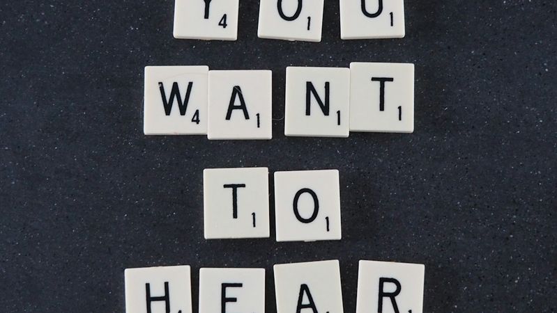 The image features a stack of letter tiles arranged to spell out the phrase 'DO YOU WANT TO HEAR BETTER' against a dark background. The tiles are likely made of plastic or a similar material, and the arrangement suggests a playful or interactive concept.