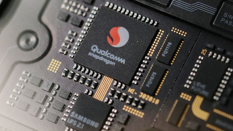 The image showcases a close-up view of a smartphone's internal circuitry, prominently featuring a Qualcomm Snapdragon processor alongside Samsung components. The intricate design highlights modern technology used in mobile devices.