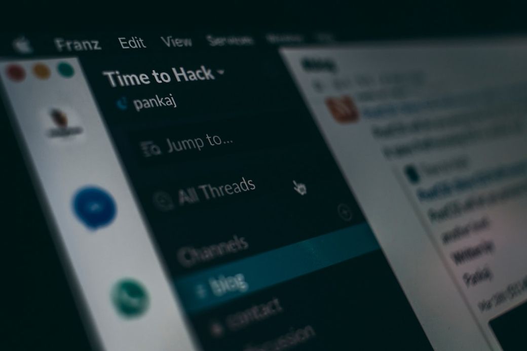 The image depicts a close-up view of a computer screen displaying a digital communication platform. Visible elements include a menu on the left titled 'Time to Hack' and various channels, indicating a collaborative workspace. — Credit: Photo by Pankaj Patel on Unsplash