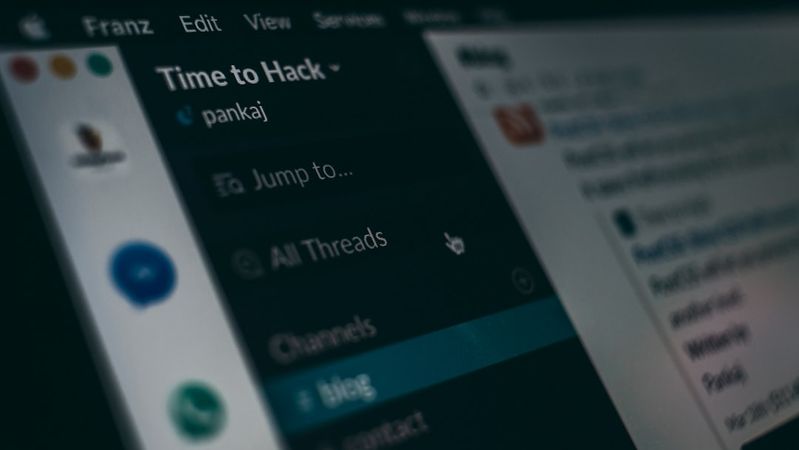 The image depicts a close-up view of a computer screen displaying a digital communication platform. Visible elements include a menu on the left titled 'Time to Hack' and various channels, indicating a collaborative workspace.