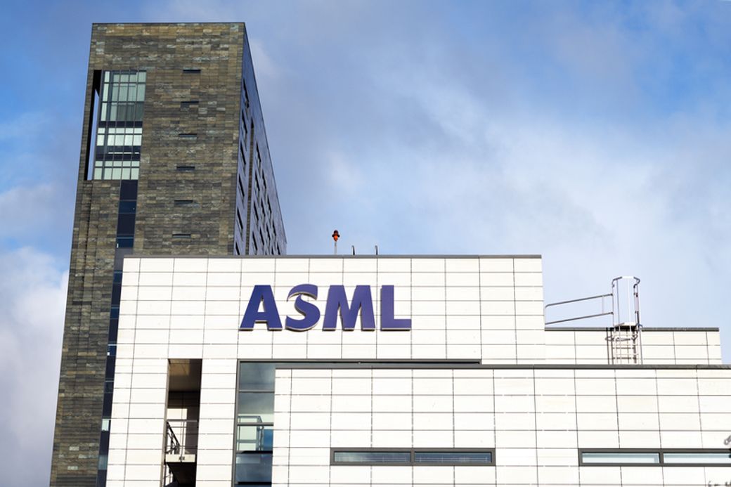 The image shows the exterior of the ASML building, featuring modern architecture. The facade is primarily white with a large, prominent ASML logo displayed.