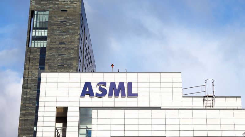 The image shows the exterior of the ASML building, featuring modern architecture. The facade is primarily white with a large, prominent ASML logo displayed.