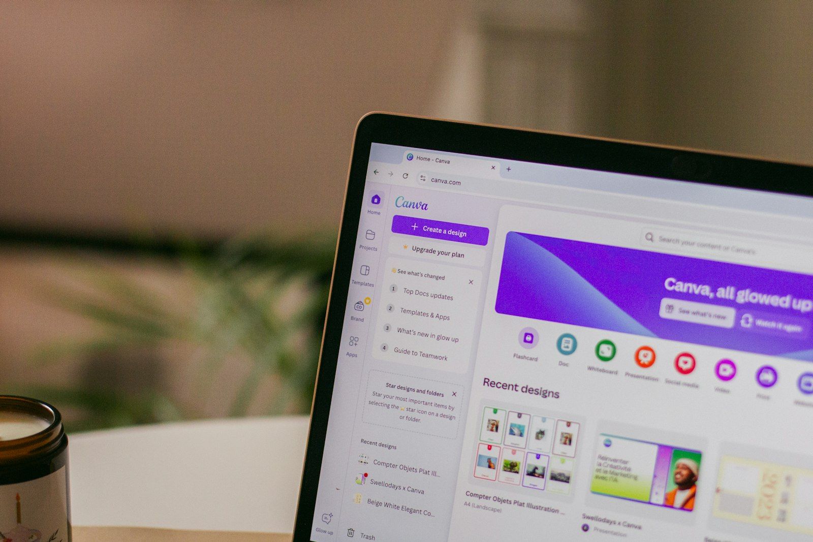 The image showcases a laptop screen displaying the Canva website, highlighting design templates and options. The interface features a modern, user-friendly design with a vibrant color scheme.