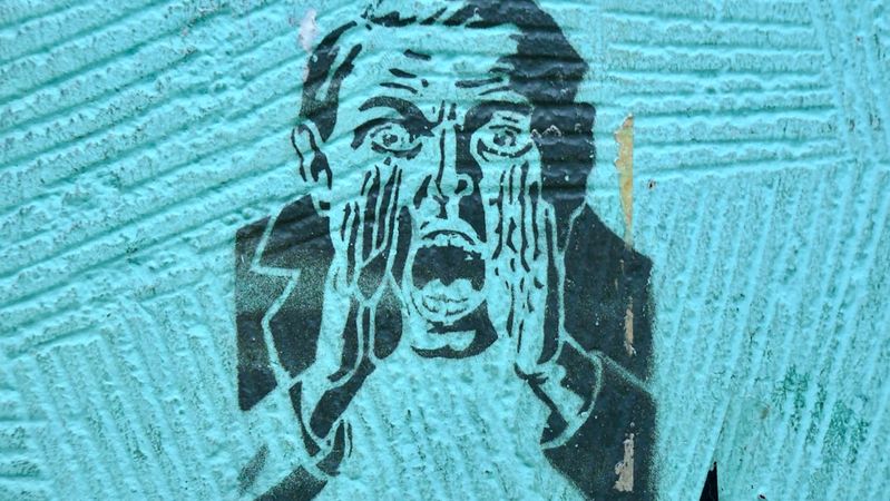 The image features a stencil graffiti art depicting a man screaming with his hands cupped around his mouth. The background is a textured turquoise surface that enhances the boldness of the artwork.