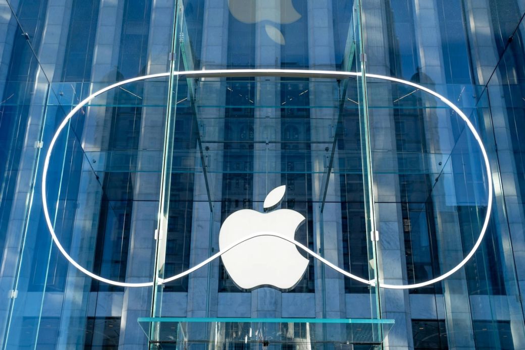 The image shows the exterior of an Apple retail store featuring a large, iconic Apple logo against a glass facade. The modern architectural design highlights the transparency and sleekness of the building's structure. — Credit: Photo by Roméo A. / Unsplash