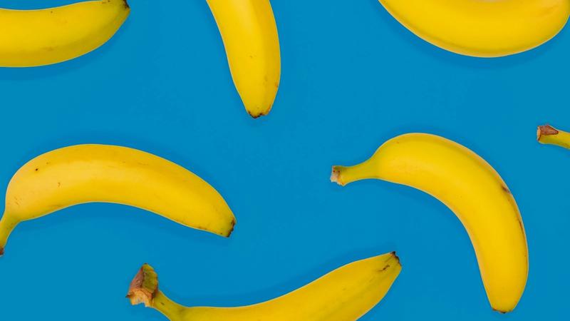 The image features several ripe bananas arranged against a bright blue background. The vibrant contrast highlights the yellow color of the bananas, creating a visually appealing composition.