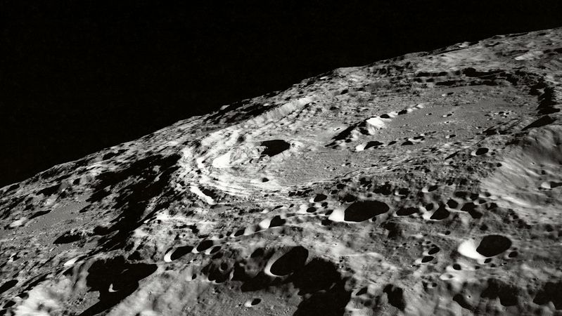 The image depicts a close-up view of the moon's surface, showcasing its craters and rugged terrain. The contrast between light and shadow emphasizes the texture of the lunar landscape.