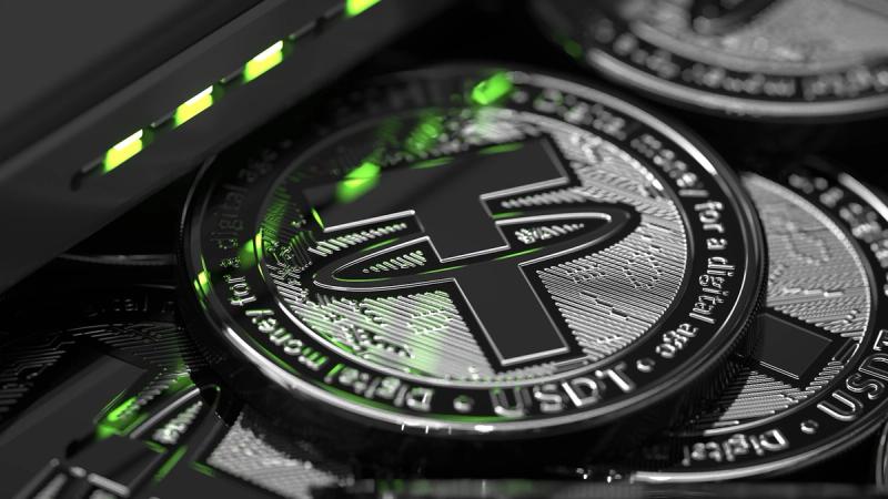 The image features a close-up view of cryptocurrency tokens with the Tether symbol prominently displayed. The tokens are shown alongside a device that appears to be a cryptocurrency wallet, illuminated by green lights.