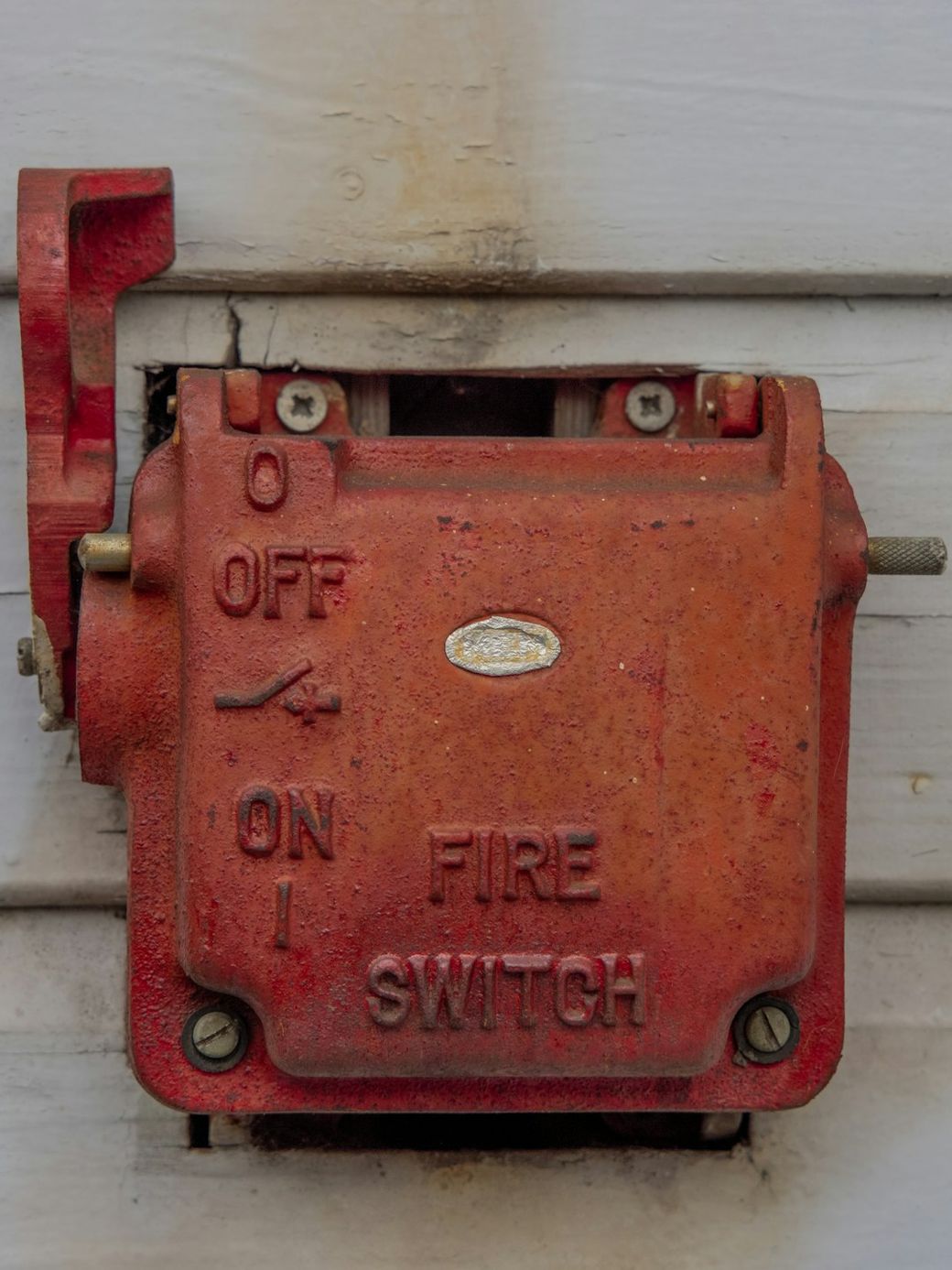 The image shows a vintage red fire switch mounted on a wall. The switch is labeled with clear instructions for 'OFF' and 'ON' settings, along with the word 'FIRE'. — Credit: Photo by the blowup on Unsplash