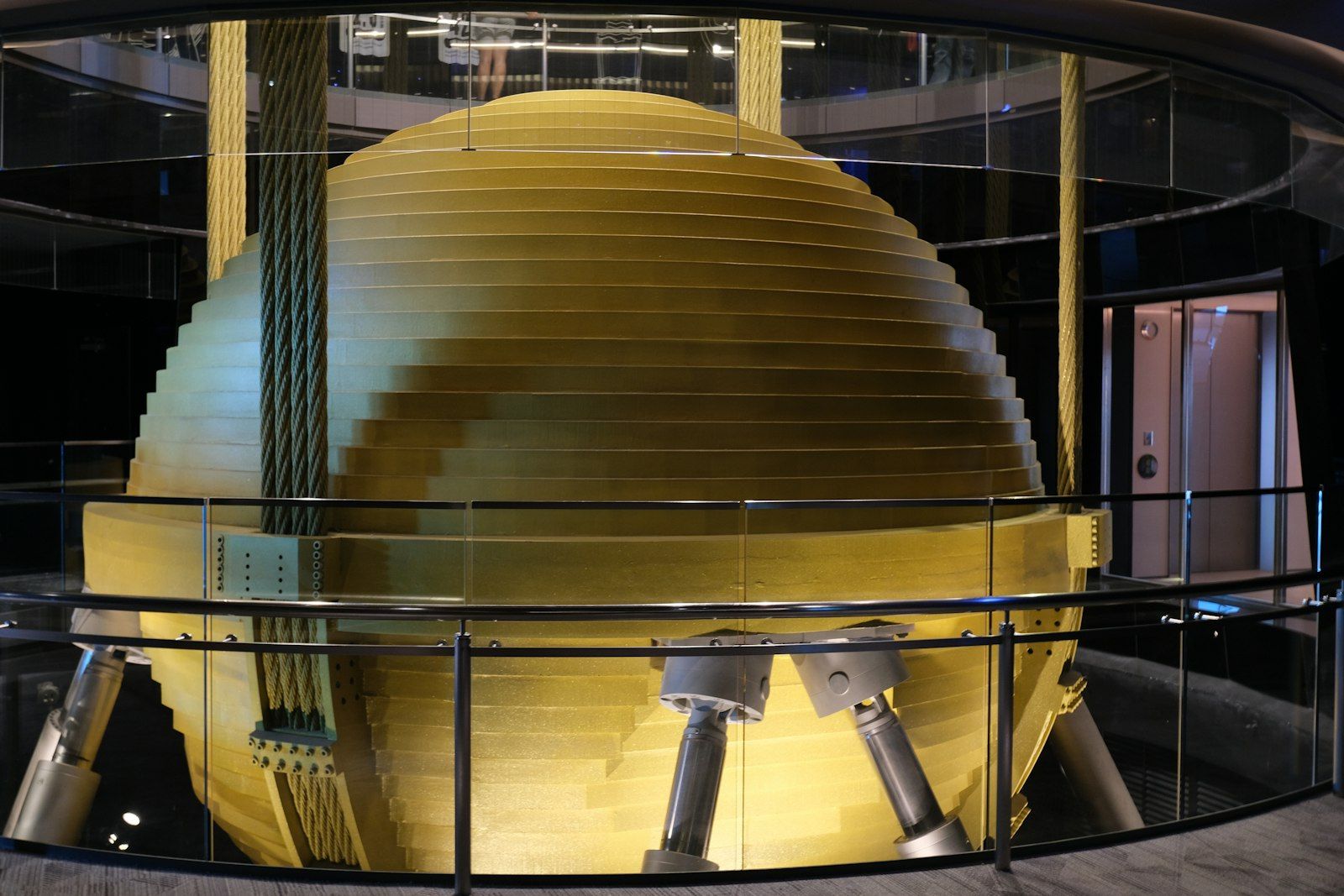 The image showcases a large, spherical object with a layered, striped design, situated within a circular glass enclosure. The environment appears to be modern and high-tech, possibly part of a scientific exhibition or advanced research facility.