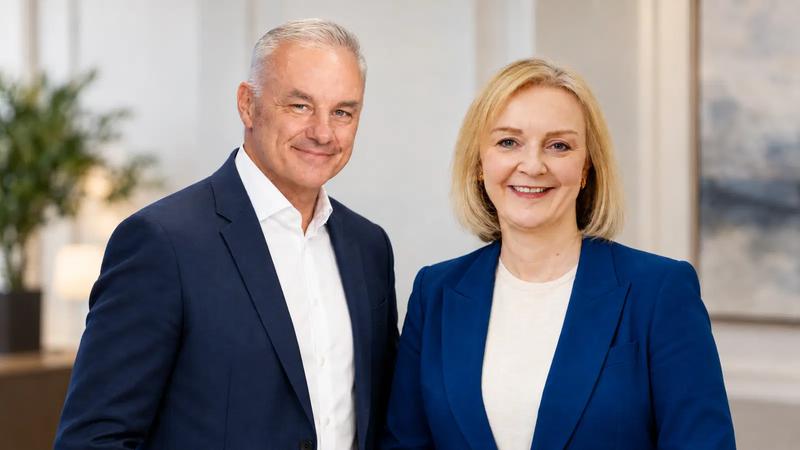 A professional portrait featuring two individuals, a man and a woman, smiling confidently at the camera. They are dressed in formal attire, suggesting a professional or corporate setting.