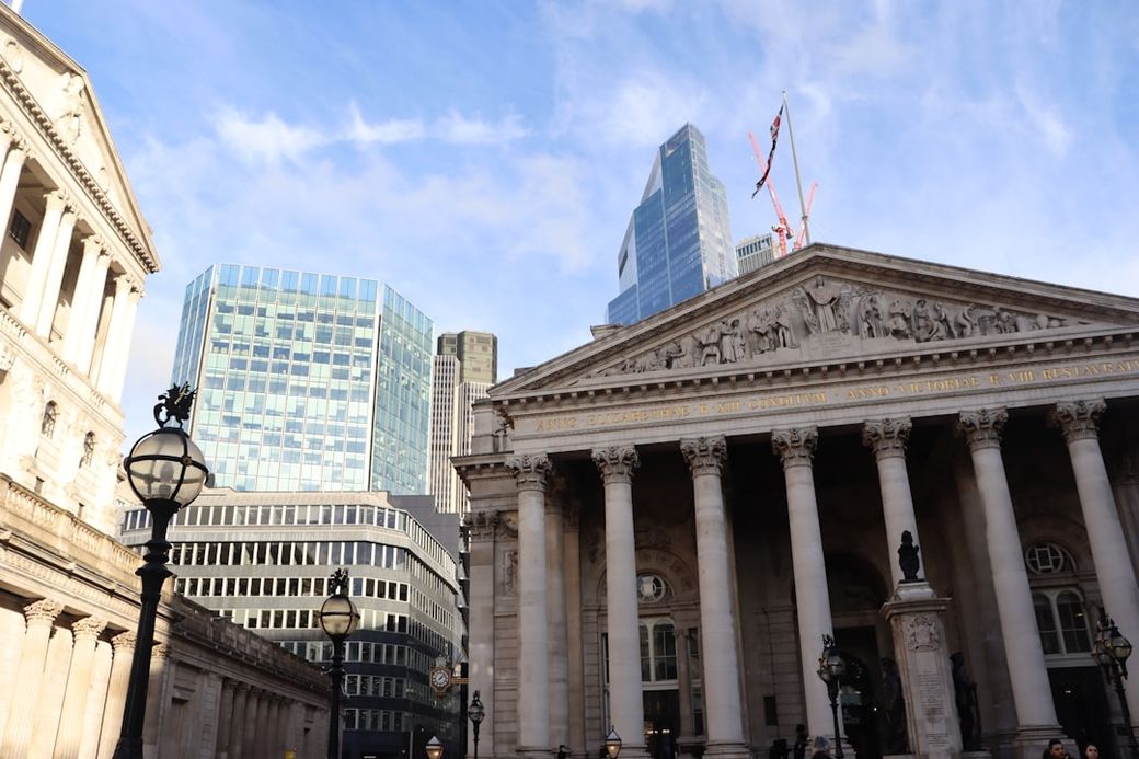 The image features the exterior of a historic building with classical architectural elements, set against a backdrop of modern skyscrapers in a city environment. The contrast between the traditional and contemporary structures highlights the evolution of urban architecture. — Credit: Photo by Alicja Ziajowska on Unsplash