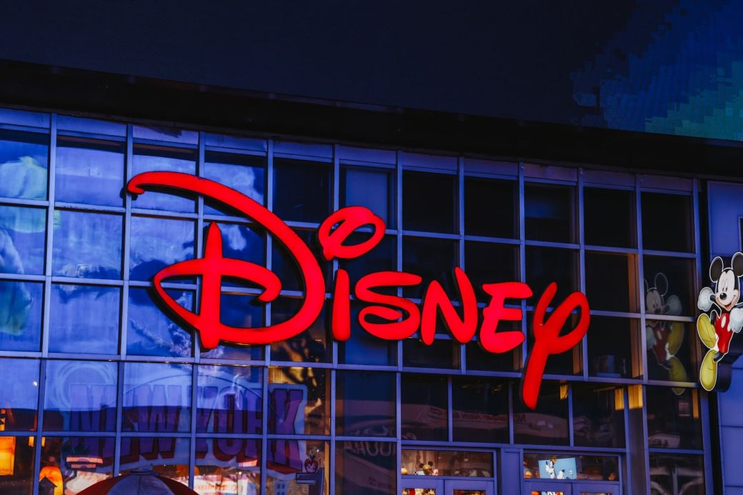 The image features a vibrant storefront of a Disney retail location, prominently displaying the iconic Disney logo in red against a glass façade. Part of the storefront includes a colorful depiction of Mickey Mouse. — Credit: Photo by Jose Marroquin on Unsplash