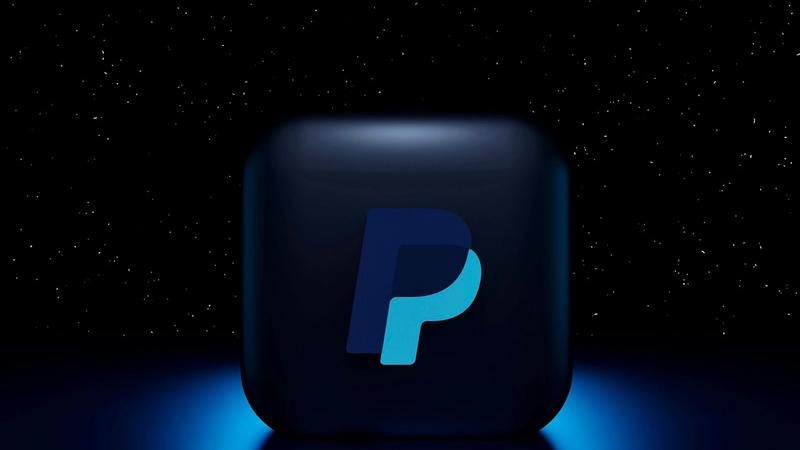 The image features a dark, glowing representation of the PayPal logo set against a starry background. The logo is highlighted in shades of blue, suggesting a modern and digital aesthetic.