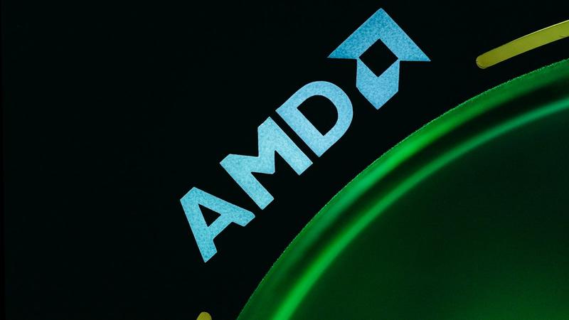 The image features a close-up of the AMD logo displayed prominently on a surface with a green circular design. The logo is brightly lit against a dark background, emphasizing the brand identity. This can represent advancements in technology or gaming.