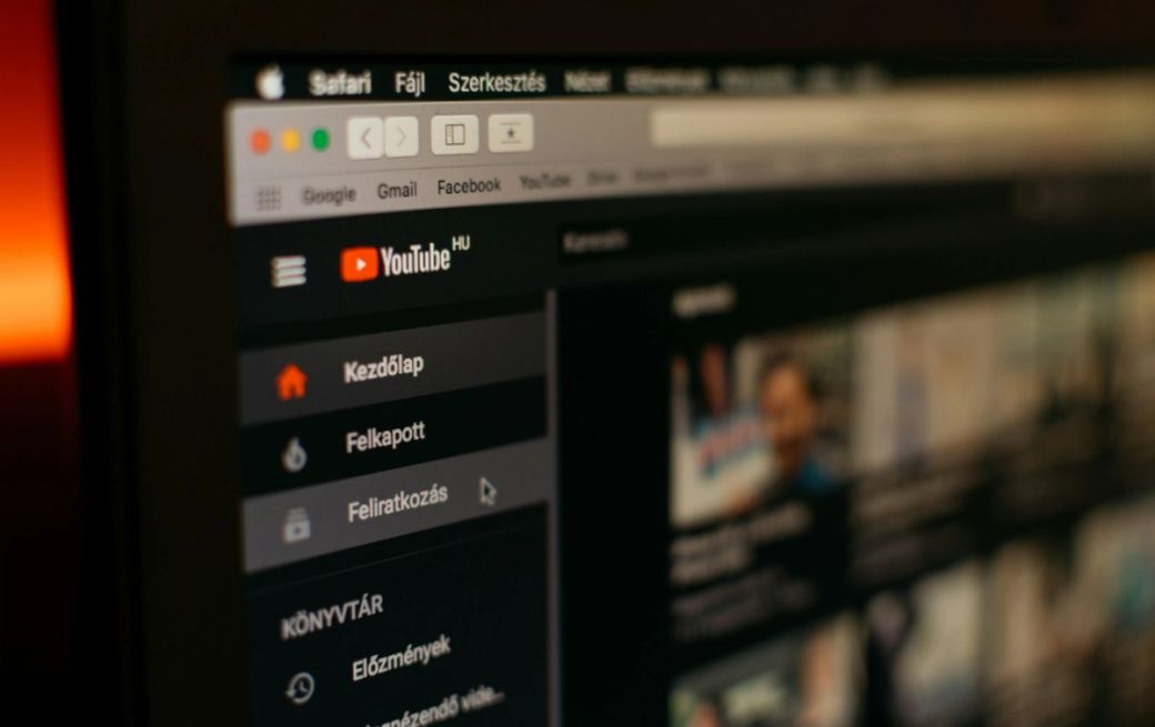 The image displays a close-up of a computer screen showing the YouTube interface in Hungarian. It features various sections like 'Kezdőlap' (Homepage), 'Felkapott' (Trending), and 'Feliratkozás' (Subscriptions), indicating user interaction with the platform. — Credit: Photo by Szabo Viktor / Unsplash