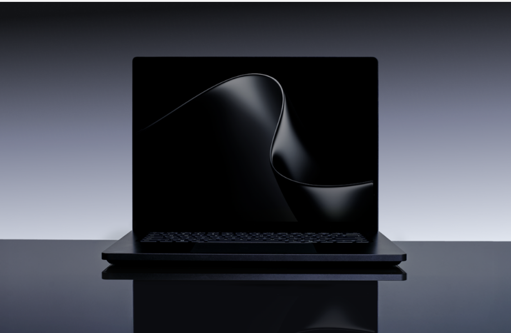The image features a sleek, modern laptop with a reflective surface, set against a minimalist gradient background. The screen displays a smooth, flowing abstract design, emphasizing the device's elegant aesthetics.