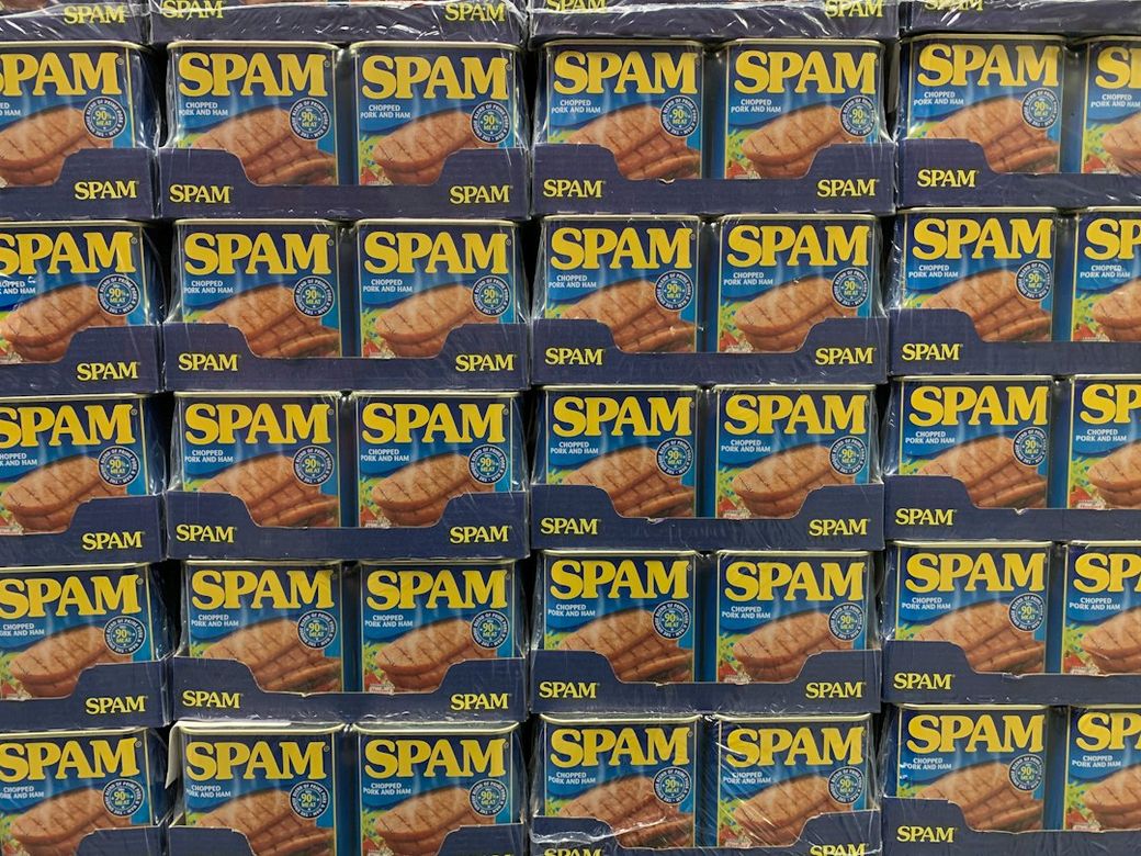An organized display of canned Spam products stacked on shelves. The packaging features bright colors and clear branding, emphasizing the product's presence in a retail environment. — Credit: Photo by Hannes Johnson on Unsplash