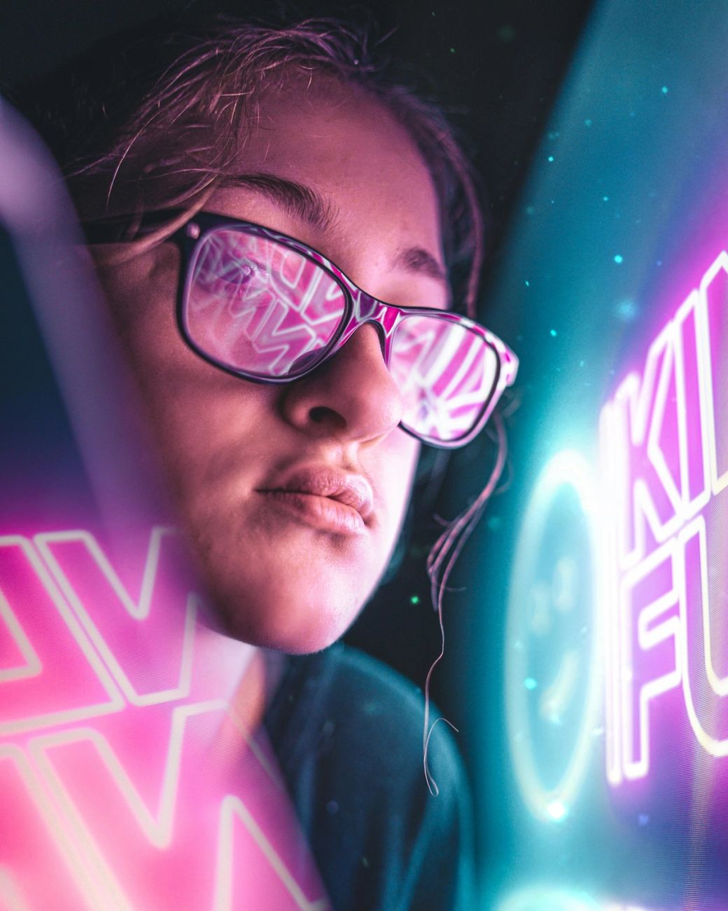 The image features a close-up of a young woman wearing glasses, with colorful reflections visible in the lenses. The background is adorned with vibrant neon text, creating a dynamic and modern atmosphere. — Credit: Photo by Bakir Custovic / Unsplash