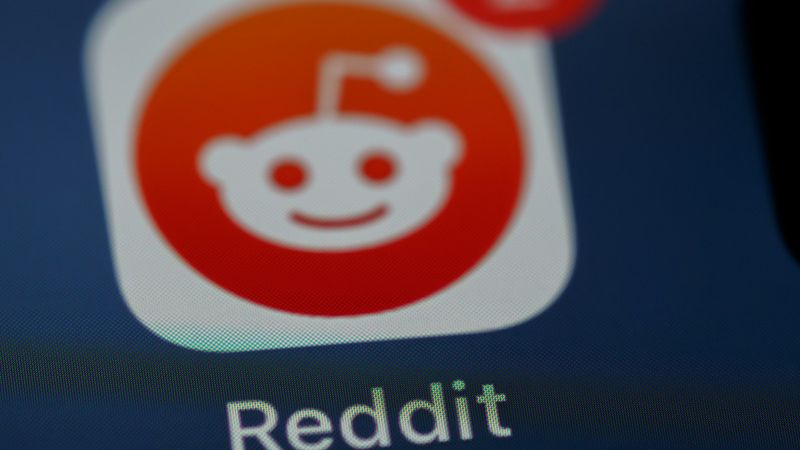 The image features a close-up view of the Reddit app icon, showcasing its distinct logo with a smiling mascot against a gradient background. A notification bubble is visible, indicating two unread messages.