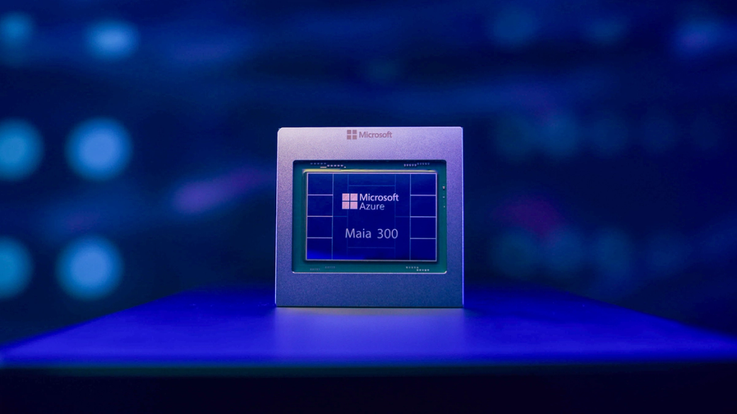 The image features a close-up of a prototype chip labeled 'Maia 300' housed within a sleek metallic frame. It is displayed against a blurred blue background, suggesting a technology-related environment, possibly related to cloud computing.
