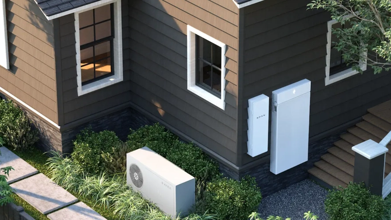 The image features a modern home with a sleek design, showcasing energy-efficient appliances and a landscape garden. Visible installation includes a home battery system positioned outside the house.