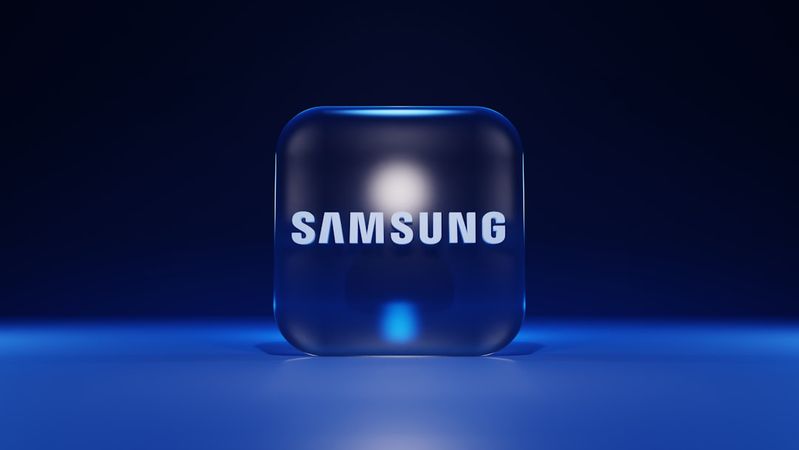 The image features a three-dimensional, illuminated cube with the Samsung logo prominently displayed on it. The background is a deep blue, creating a modern and tech-focused aesthetic.