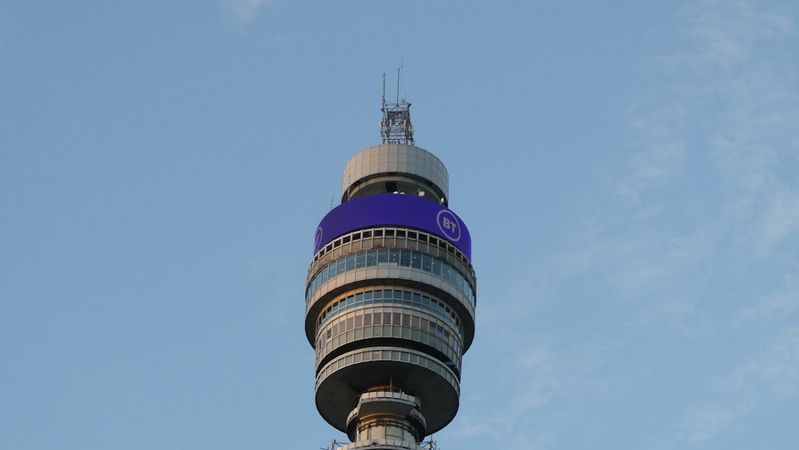 The image features the iconic BT Tower prominently against a clear blue sky. Its distinctive cylindrical shape and observation windows are highlighted, showcasing its architectural design.