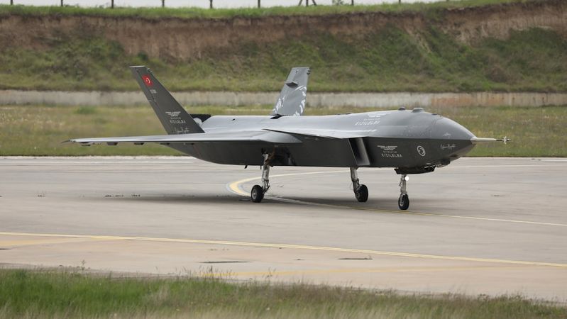 An unmanned aerial vehicle (UAV) is positioned on a runway at an airfield. The aircraft bears markings indicative of military use and is ready for takeoff, showcasing its sleek design and advanced technology.