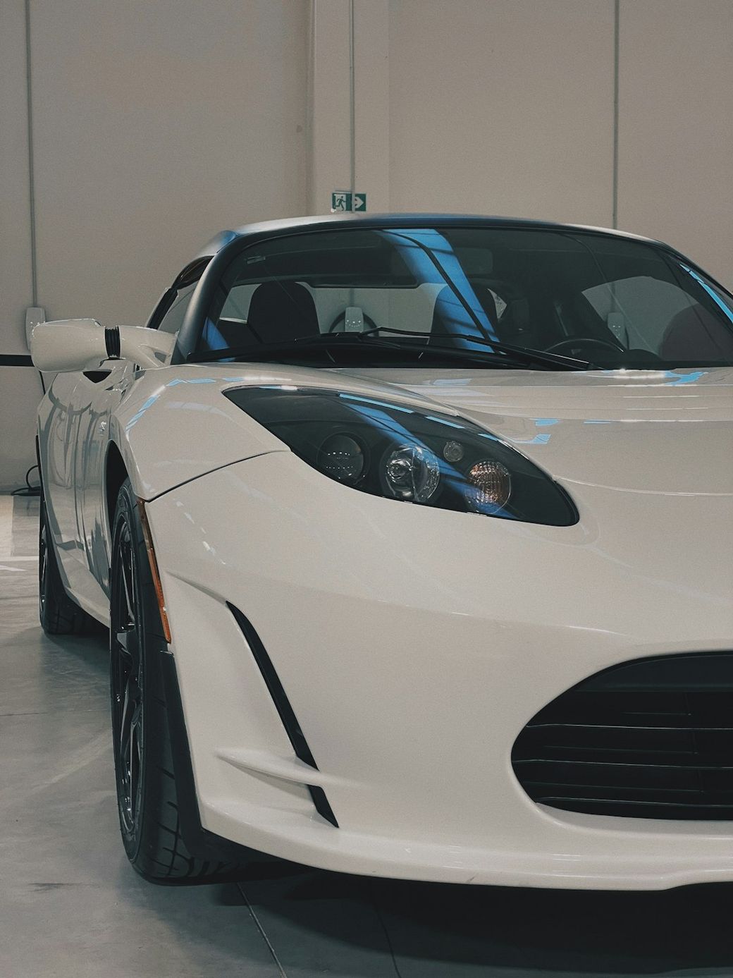 A close-up view of a sleek white sports car parked indoors. The car features a streamlined design with distinctive headlights and black accents, showcasing its modern engineering. — Credit: Photo by Michael Martinelli on Unsplash