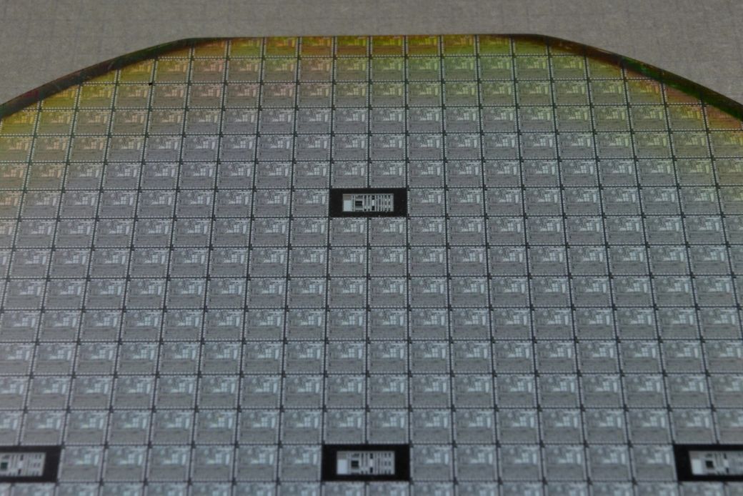 The image shows a silicon wafer, which has numerous microchips arranged in a grid pattern. This wafer is typically used in semiconductor manufacturing processes to create integrated circuits. — Credit: Photo by Laura Ockel / Unsplash