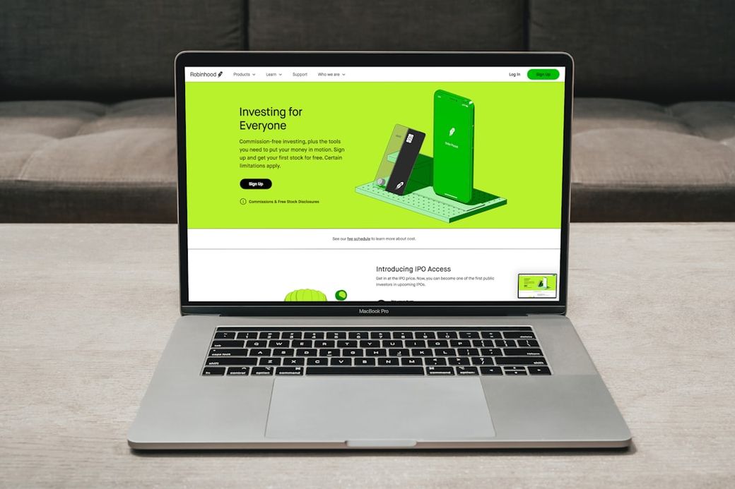 A laptop displays a digital investment platform website featuring a vibrant green design. The homepage emphasizes investment accessibility for everyone, showcasing various features of the application. — Credit: Photo by PiggyBank on Unsplash
