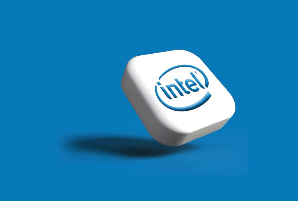 The image features a stylized representation of the Intel logo against a blue background. The logo is three-dimensional and appears to be floating, emphasizing the brand's identity in technology. — Credit: Photo by Rubaitul Azad / Unsplash