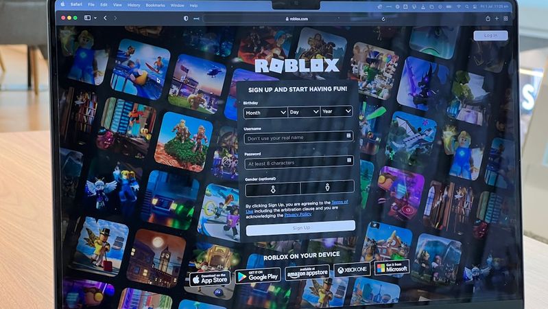 The image shows a laptop screen displaying the Roblox sign-up page. The background features a collage of various game graphics from Roblox, highlighting the platform's diverse offerings.
