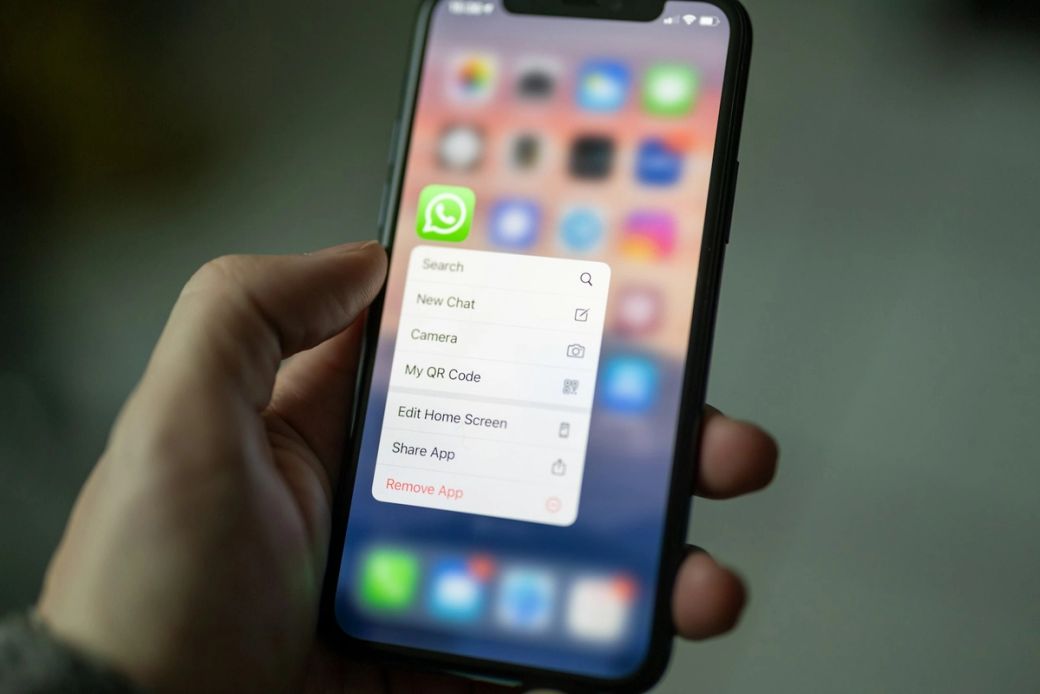 The image shows a close-up of a smartphone held in a hand, displaying a menu from the WhatsApp application. The phone's screen includes various icons and options related to WhatsApp functions. — Credit: Photo by Dimitri Karastelev / Unsplash