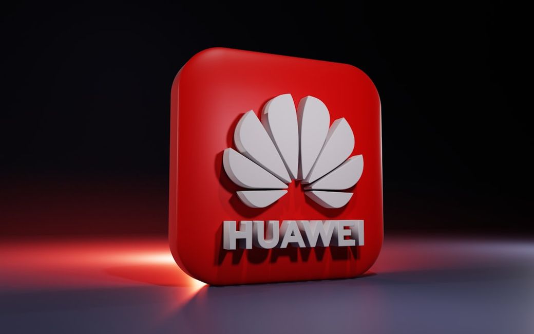 The image features a three-dimensional rendering of the Huawei logo set against a dark background. The logo prominently displays the company's name and its iconic flower-like symbol. — Credit: Photo by BoliviaInteligente on Unsplash