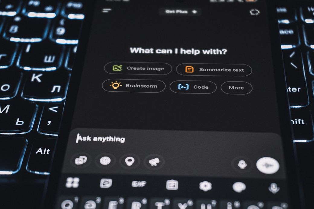 A close-up view of a smartphone interface displaying various options for assistance, such as 'Create image' and 'Summarize text'. The background features a illuminated keyboard, enhancing the tech-centric feel of the image. — Credit: Photo by Zulfugar Karimov on Unsplash