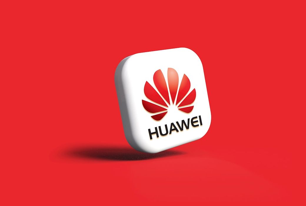 The image features a 3D rendition of the Huawei logo set against a striking red background. The logo is prominently displayed, highlighting the brand's iconic design. — Credit: Photo by Rubaitul Azad on Unsplash