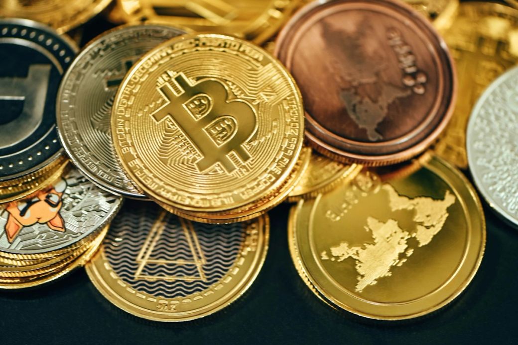 The image features a collection of various cryptocurrency coins arranged in a close-up view. Bitcoin is prominently displayed among other digital currencies, showcasing the growing diversity in the cryptocurrency market. — Credit: Photo by Traxer / Unsplash