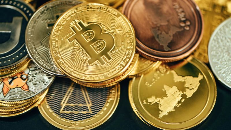 The image features a collection of various cryptocurrency coins arranged in a close-up view. Bitcoin is prominently displayed among other digital currencies, showcasing the growing diversity in the cryptocurrency market.