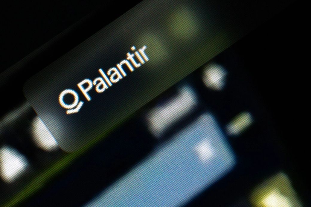 The image features a close-up view of a screen displaying the logo of Palantir Technologies. The logo is prominently displayed against a blurred background, suggesting a digital or technological context. — Credit: Photo by Salvador Rios / Unsplash