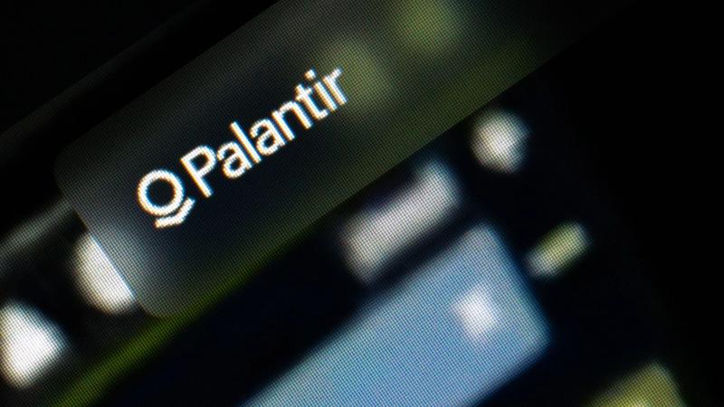 The image features a close-up view of a screen displaying the logo of Palantir Technologies. The logo is prominently displayed against a blurred background, suggesting a digital or technological context.