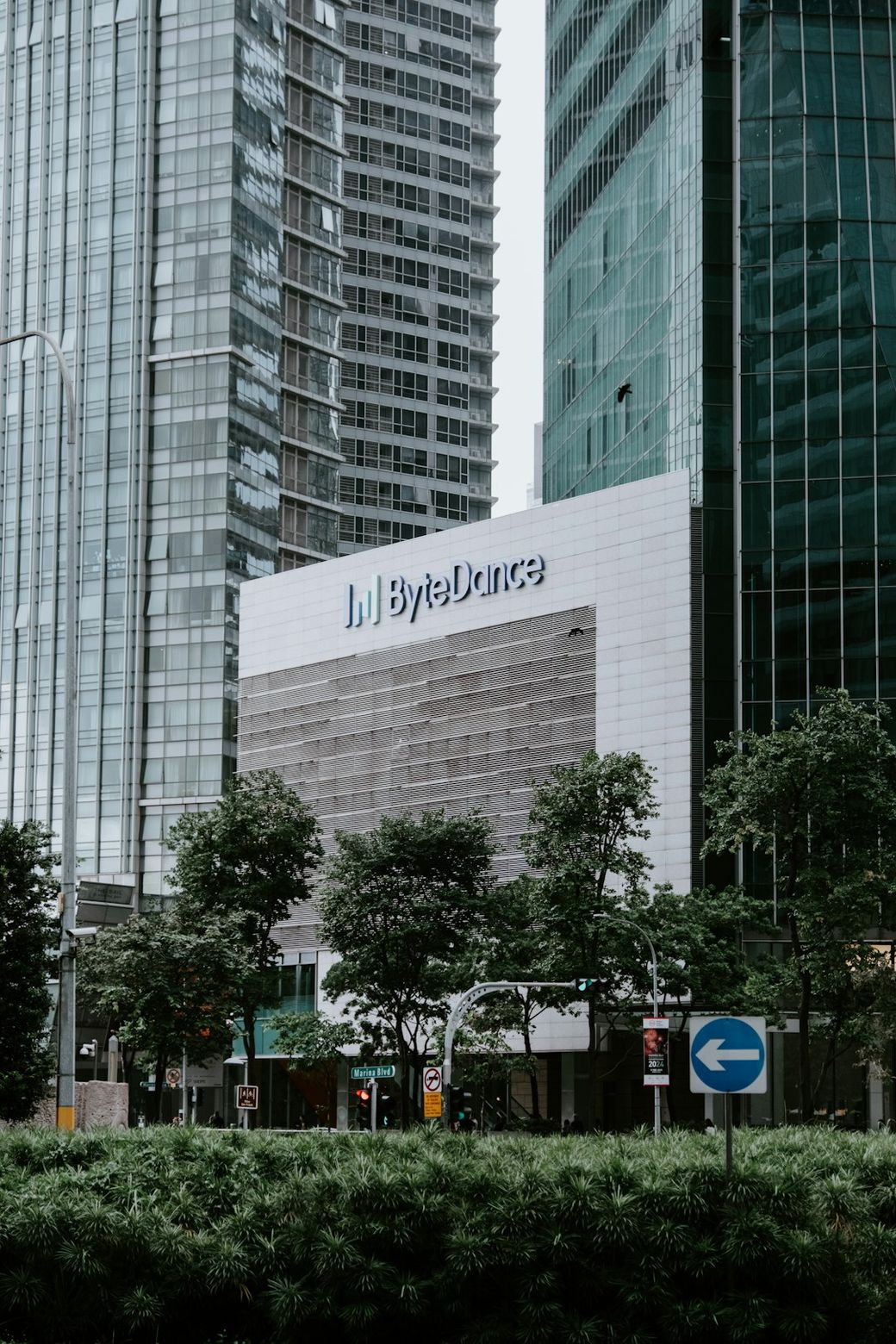 The image showcases a modern office building with a prominent ByteDance logo on its facade. Surrounding greenery and urban architecture are present, highlighting a blend of nature and contemporary design. — Credit: Photo by Claudio Schwarz on Unsplash